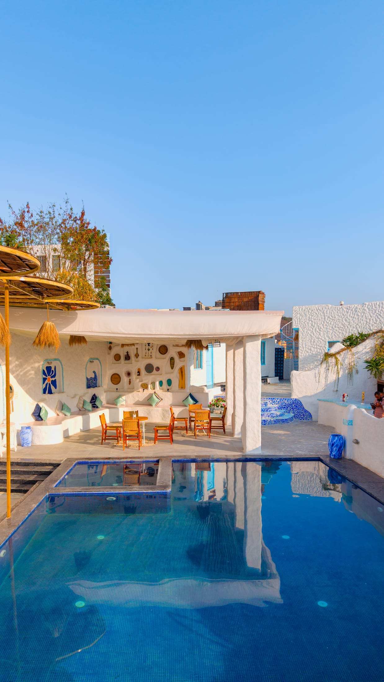 Aerial view of the pool and covered pavilion with blue and white decor beside the terrace café
