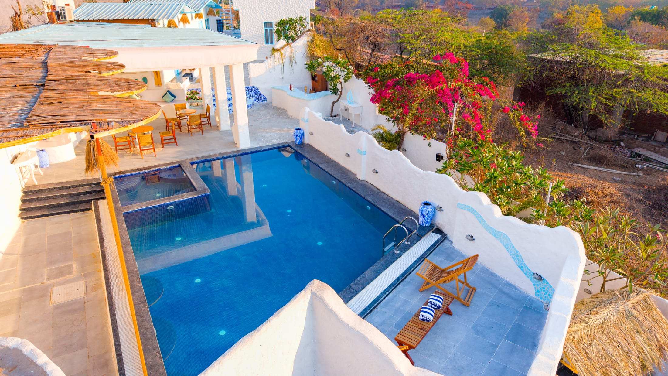 Top view of the private blue swimming pool at Dyna Udaipur with sun loungers and white terraces