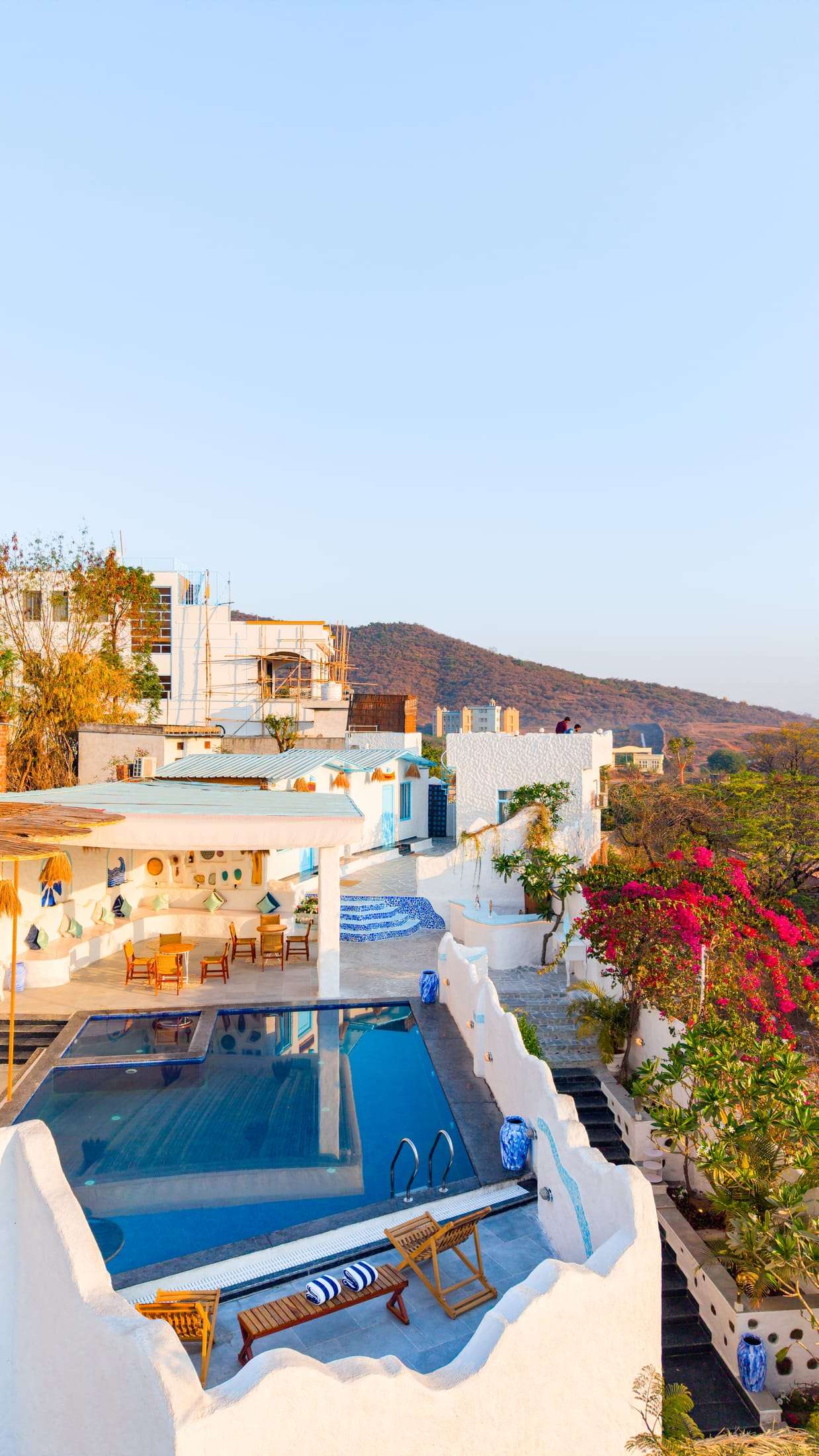 Aerial view of Dyna, a whitewashed Santorini-style villa with a terrace and pool against the Aravalli hills in Udaipur