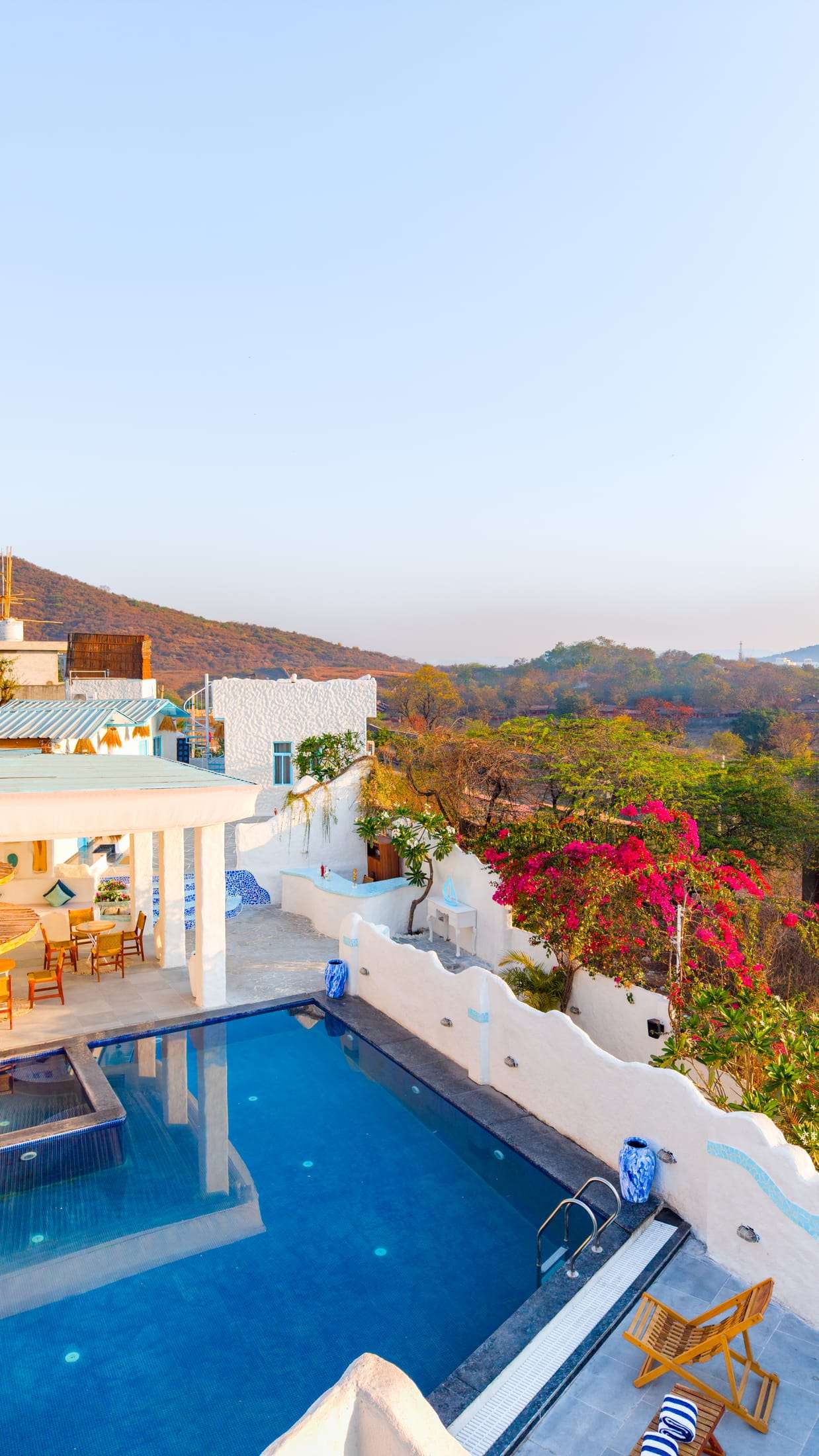 Drone shot of the villa terrace and pavilion with pink bougainvillea and Aravalli hills behind