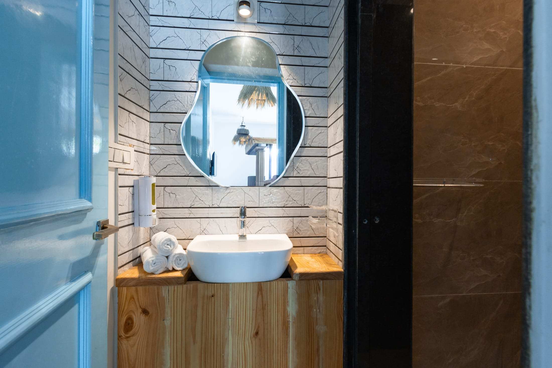 Attached bathroom in Athena's Alcove with a round mirror and wooden vanity