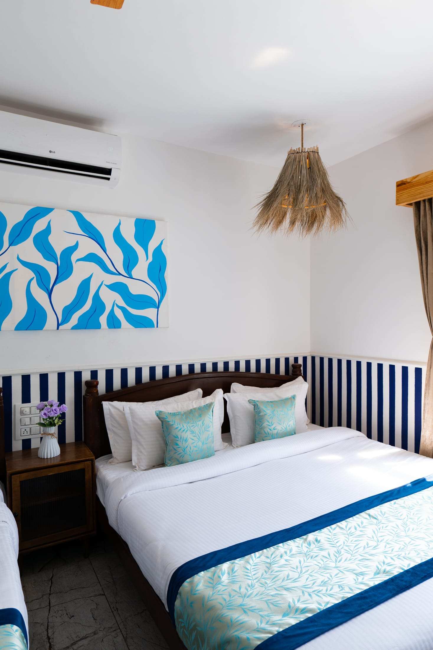 King bed with teal cushions beneath blue leaf artwork in Athena's Alcove