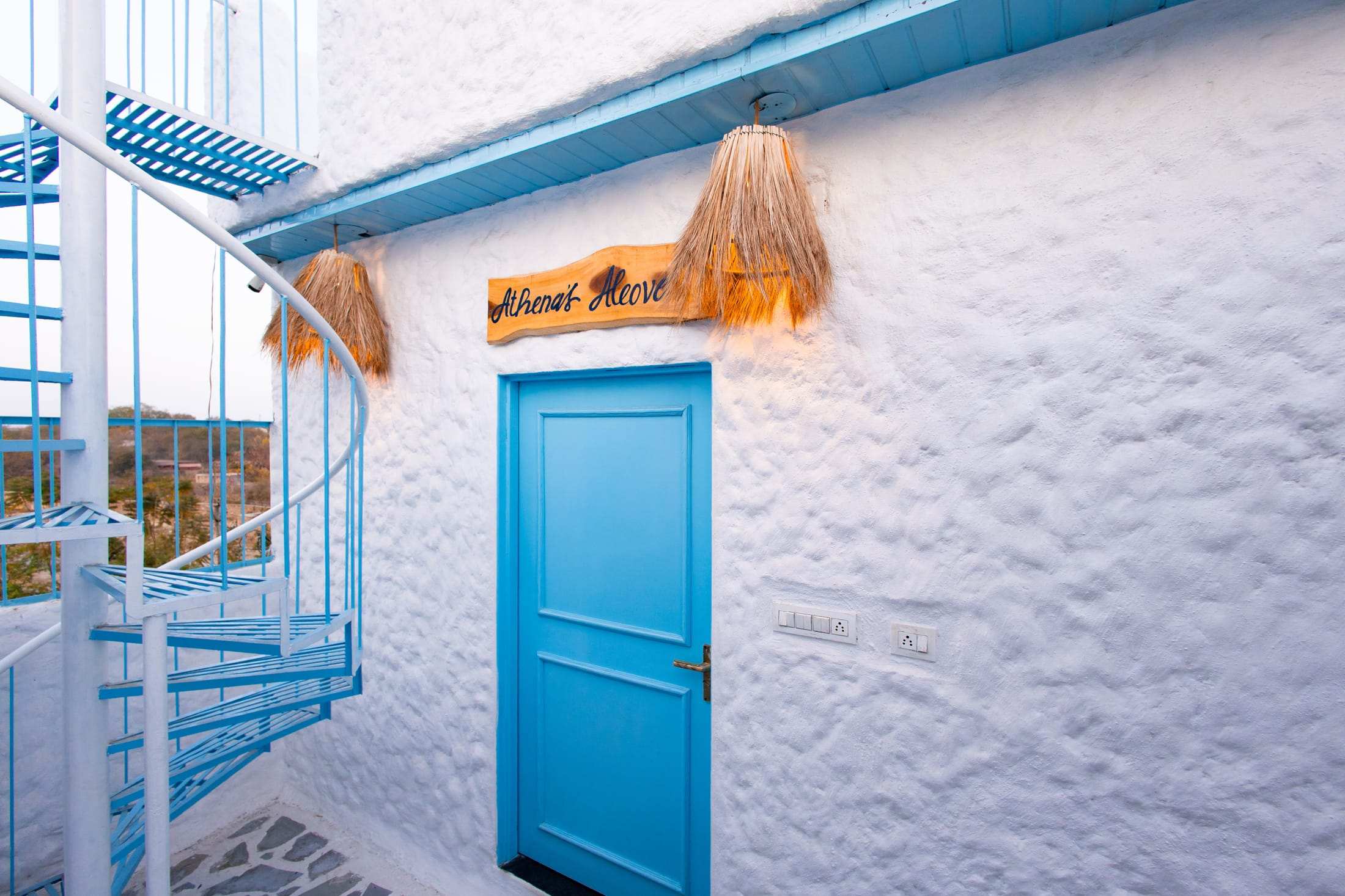 Blue door and thatched sign at the entrance to Athena's Alcove