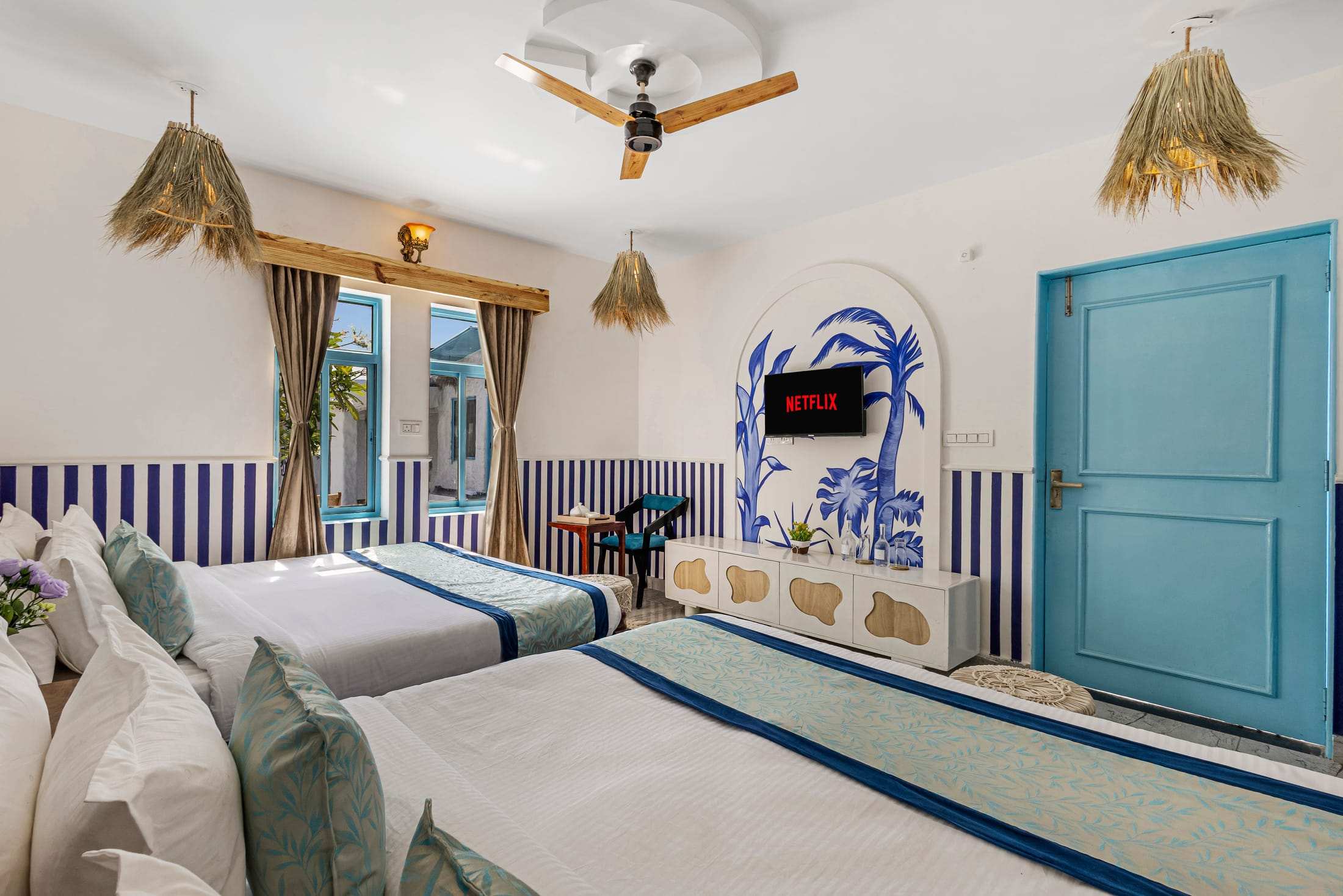 Athena's Alcove TV wall with a hand-painted palm mural and a blue arched door