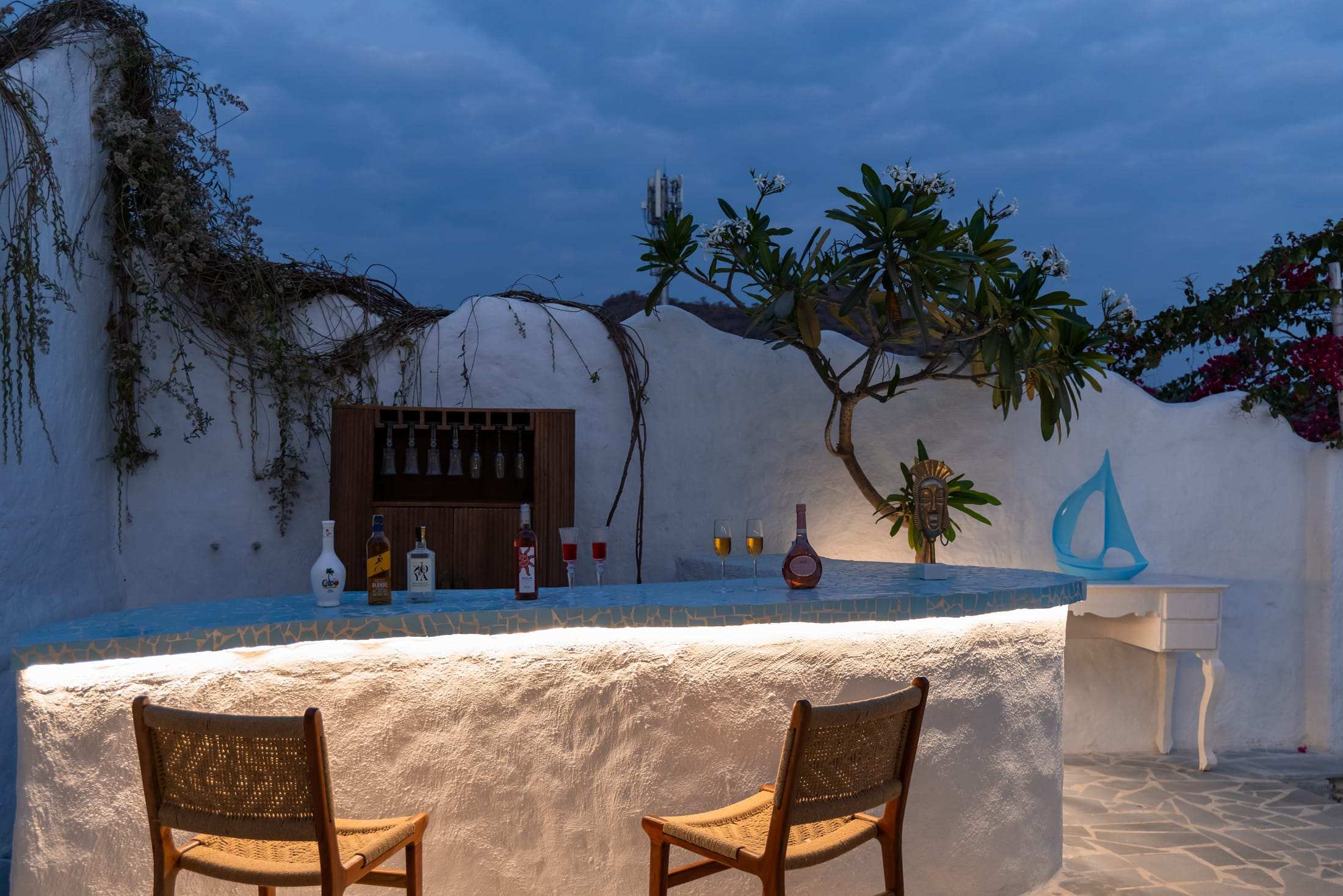 Whitewashed bar counter with warm underlighting and bottles on the shelf