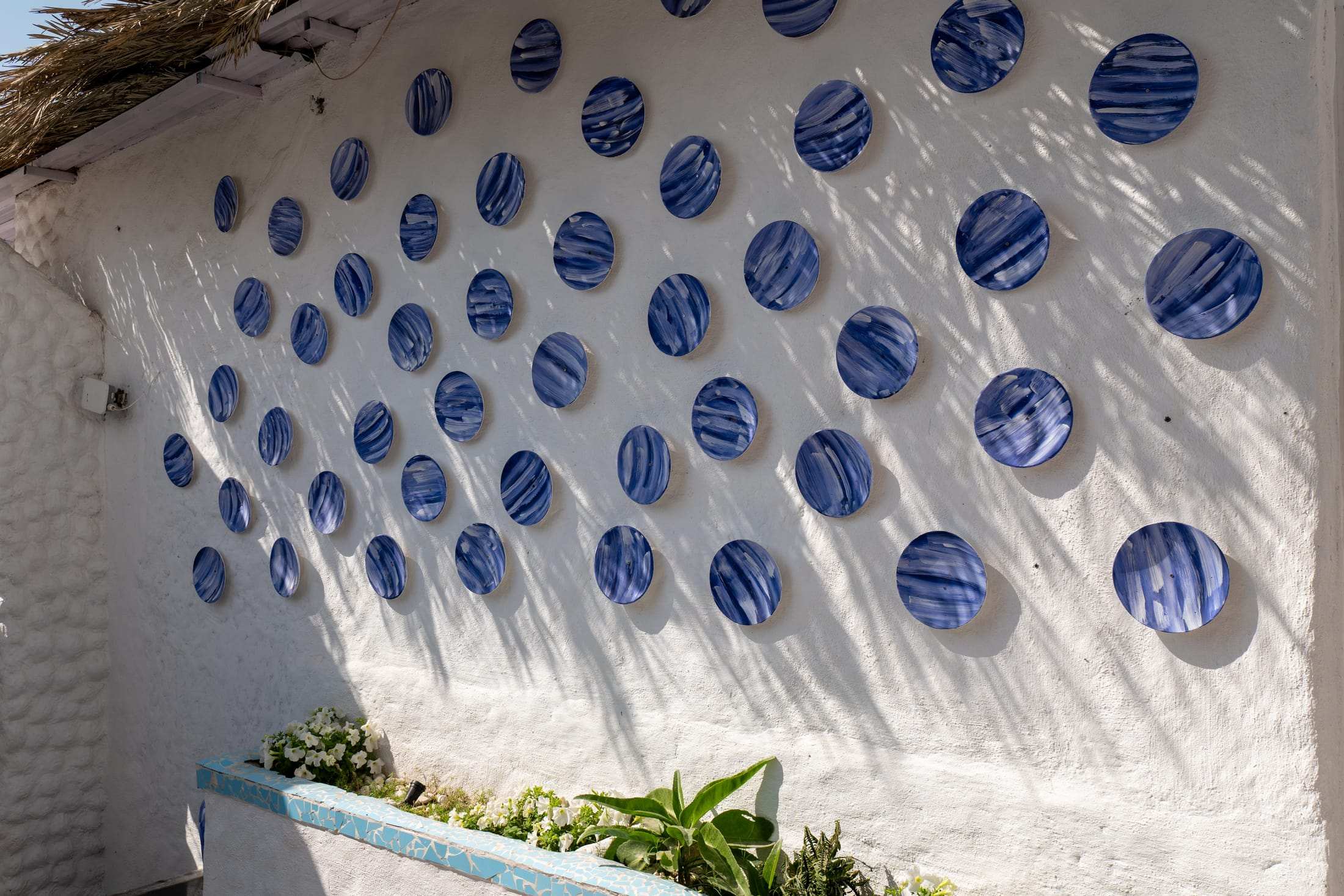 White wall covered in blue ceramic plates in a Greek-style pattern