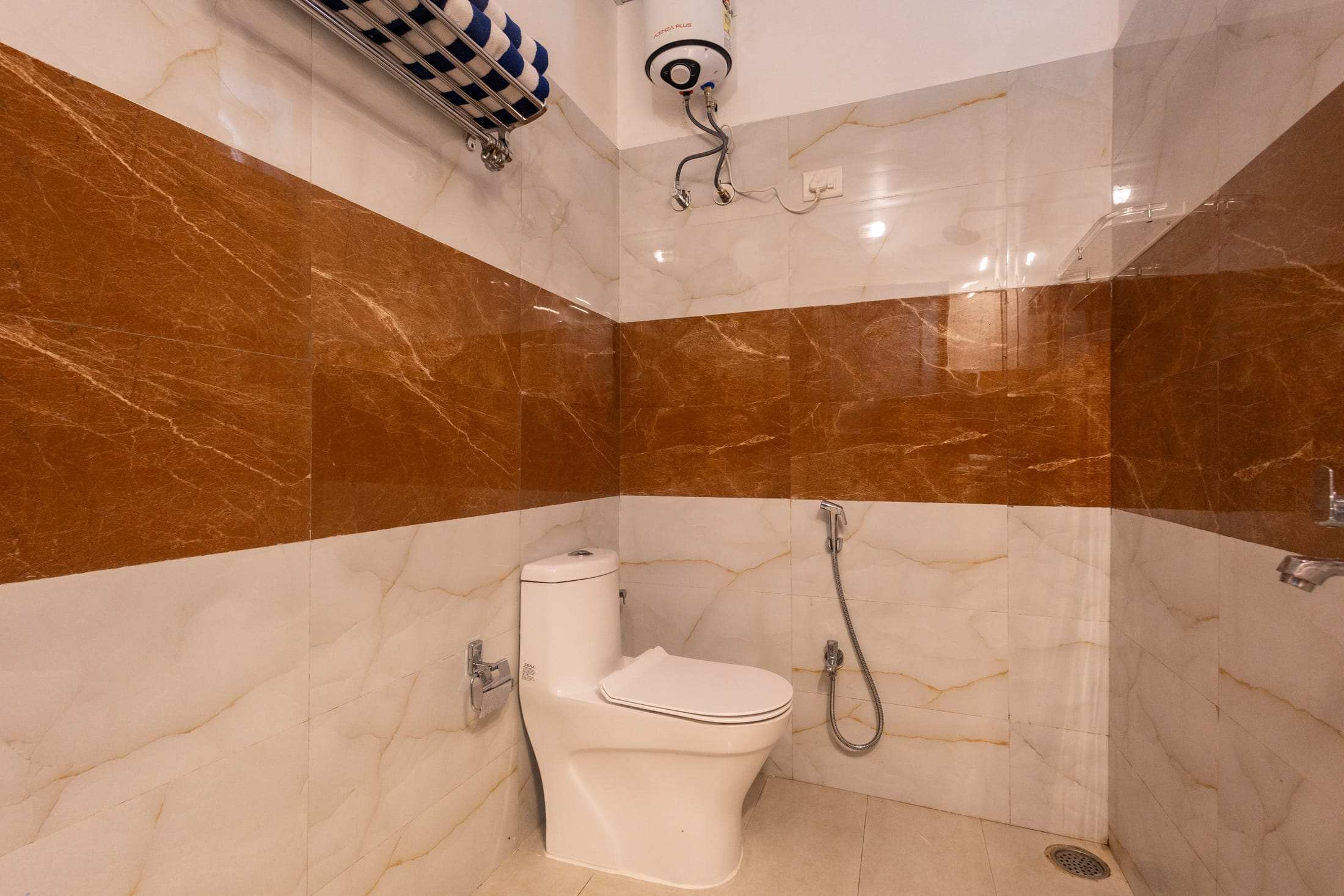 Bathroom with warm marble tiles and a rain shower in the Blue & White Retreat