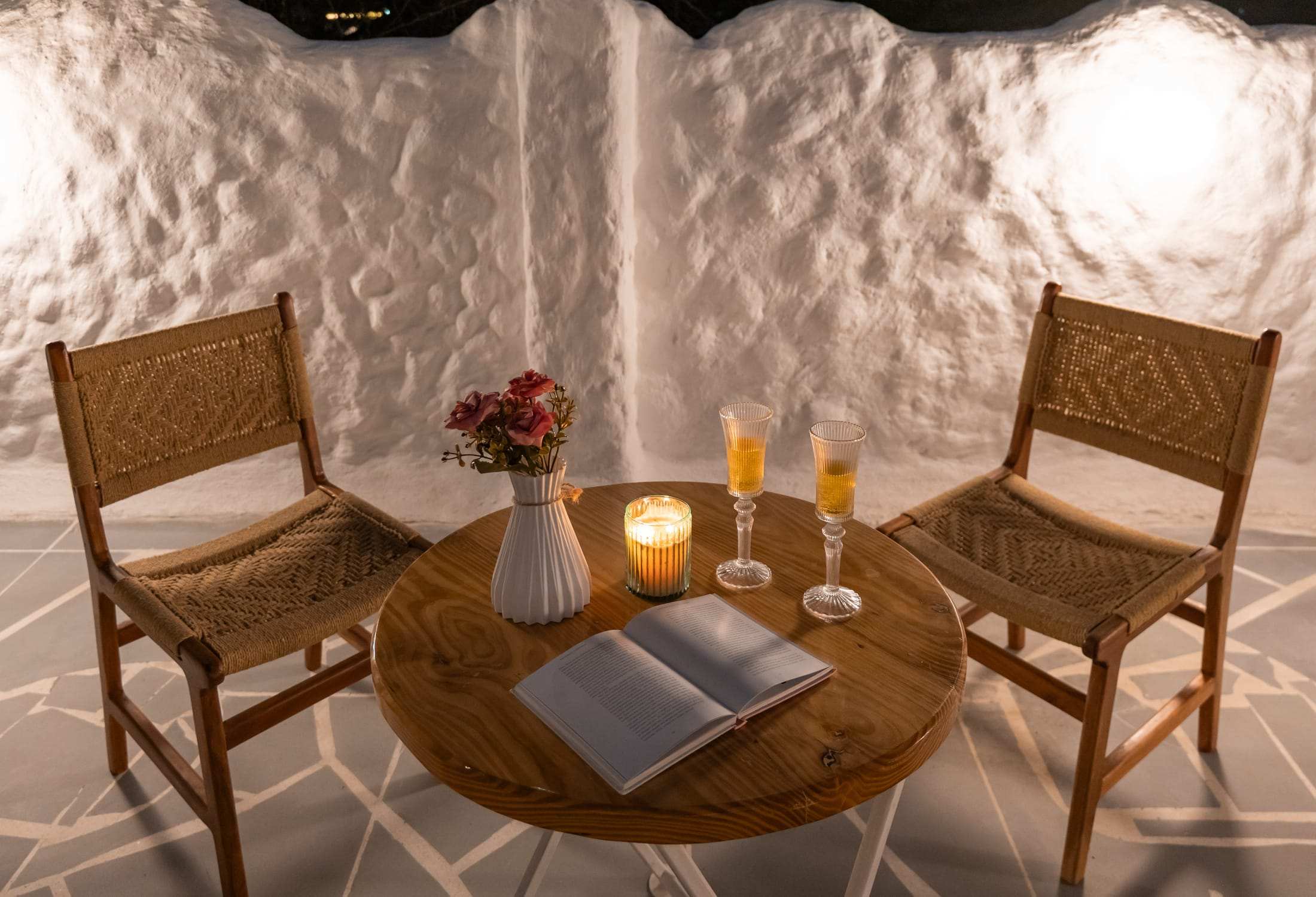Candlelit table with drinks and a book on the terrace