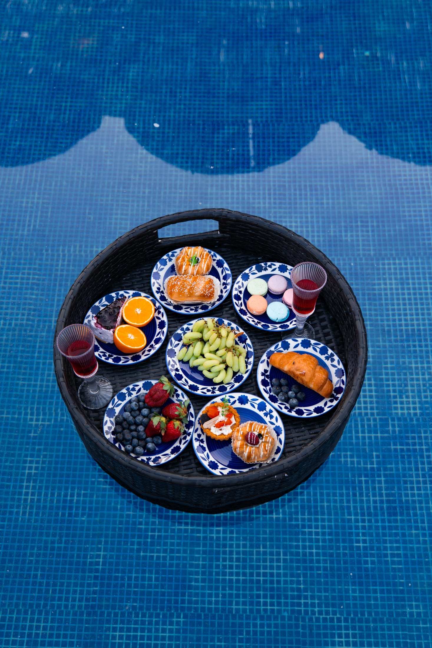Floating breakfast tray with fruit, pastries and juice in the blue pool