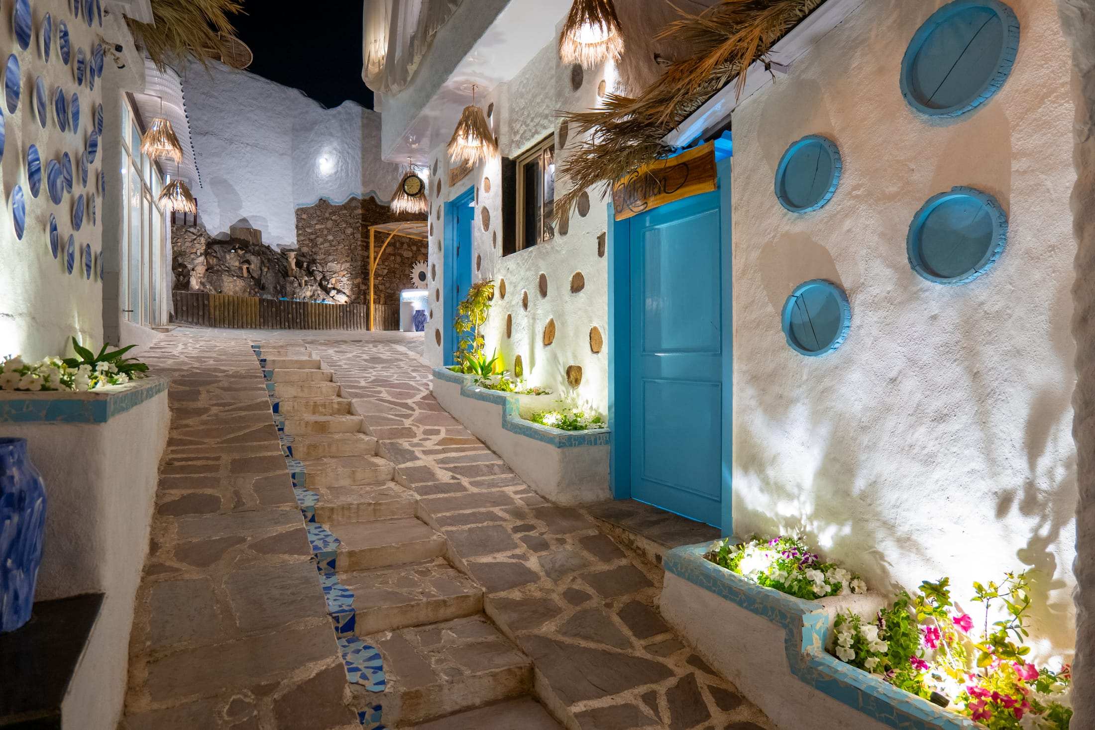 Stone lane with blue doors, round window cut-outs and flower planters