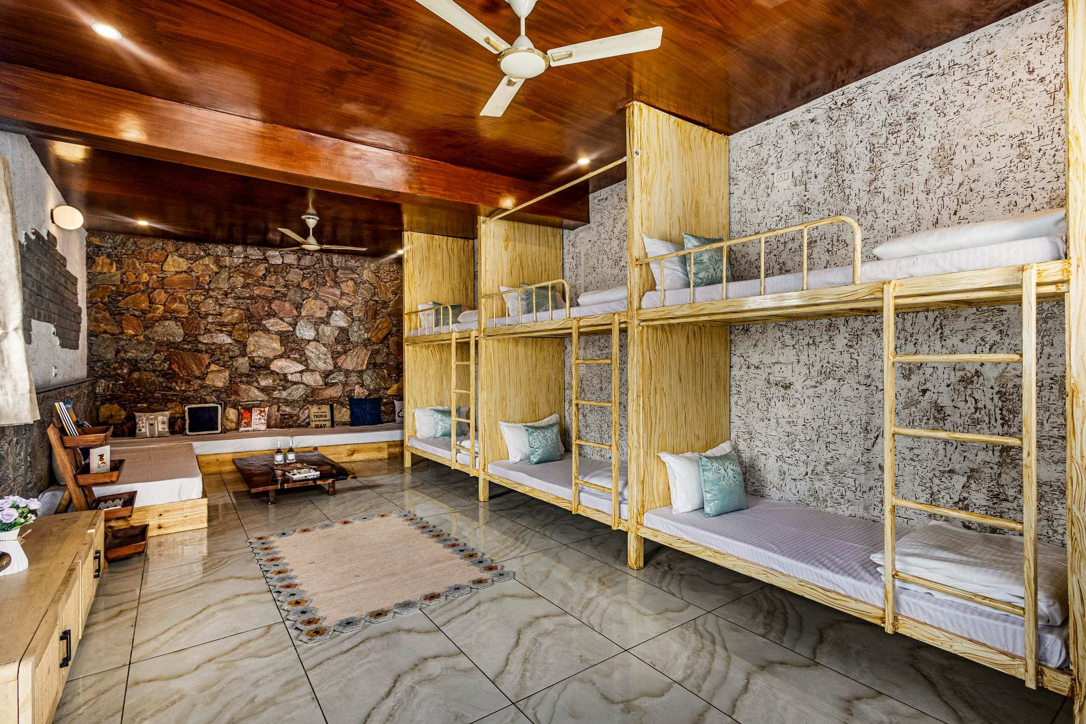 Noe's Nest dormitory with wooden bunk beds along a stone feature wall