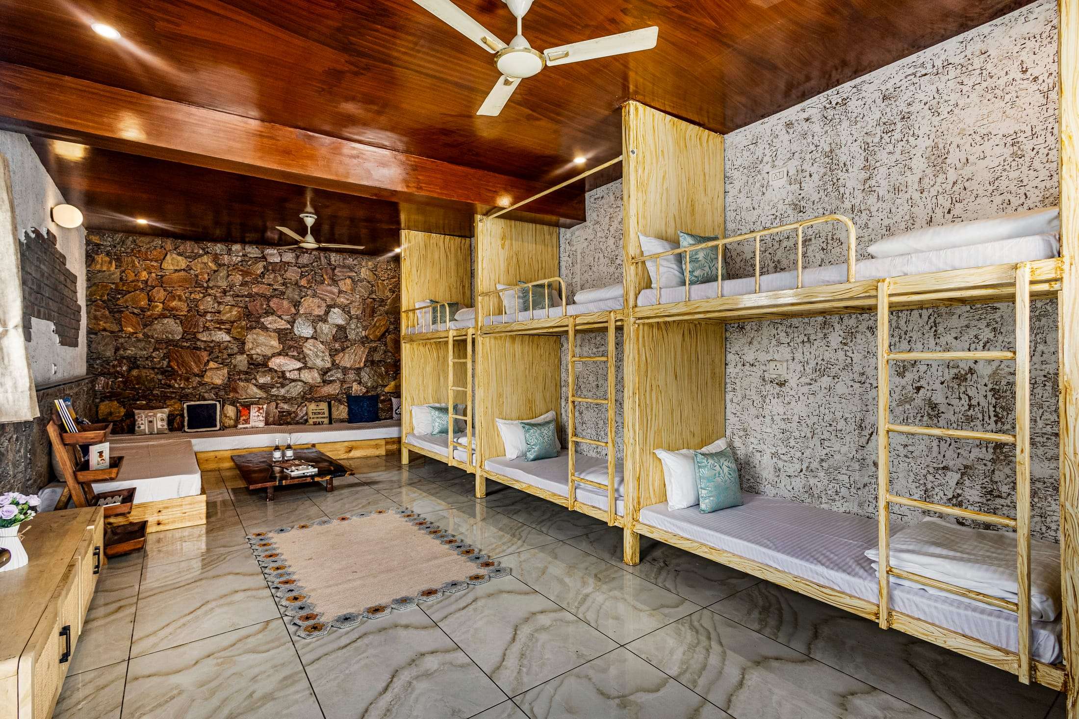 Noe's Nest dormitory with wooden bunk beds along a stone feature wall