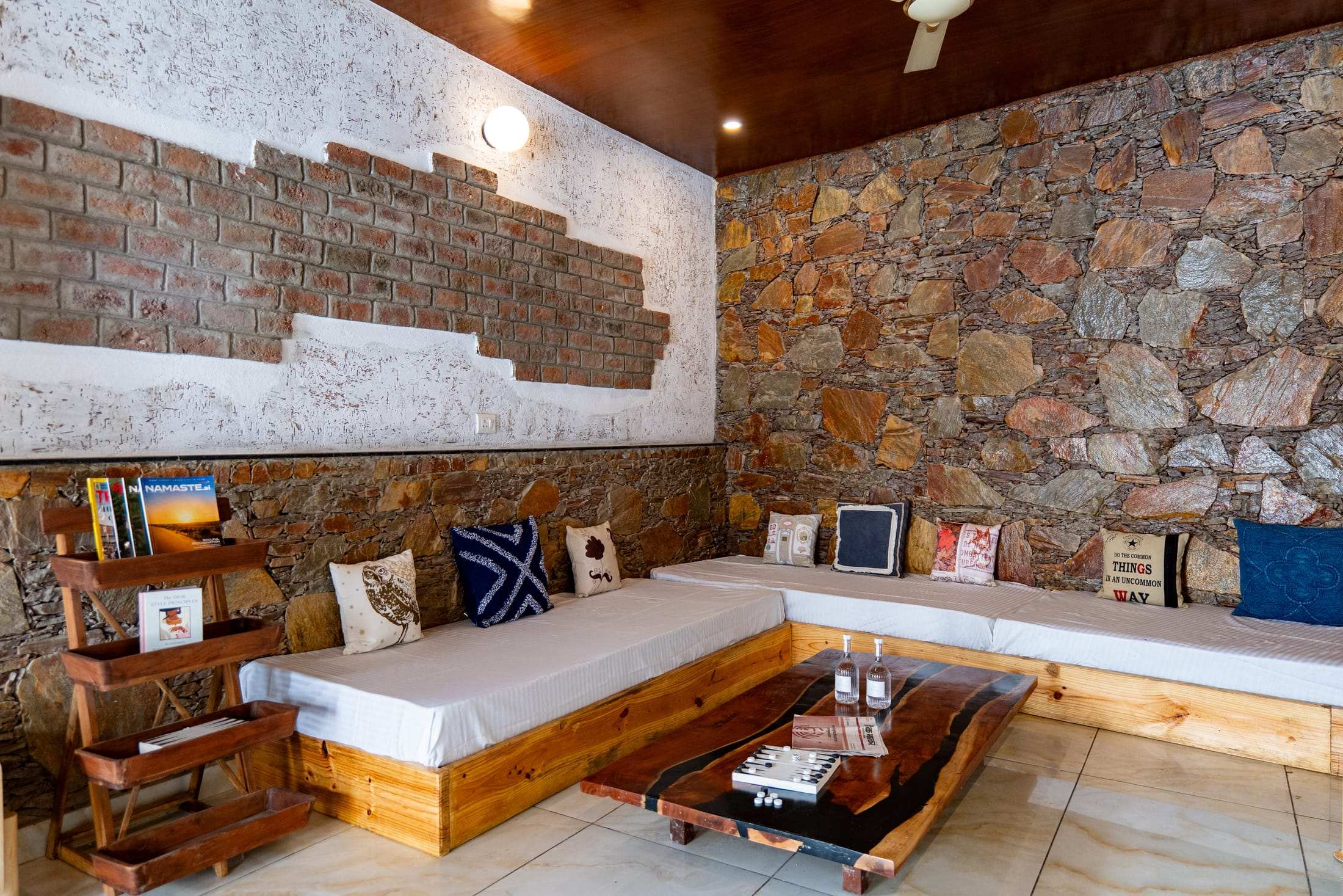Sofa seating with a bookshelf and cushions beside a stone wall