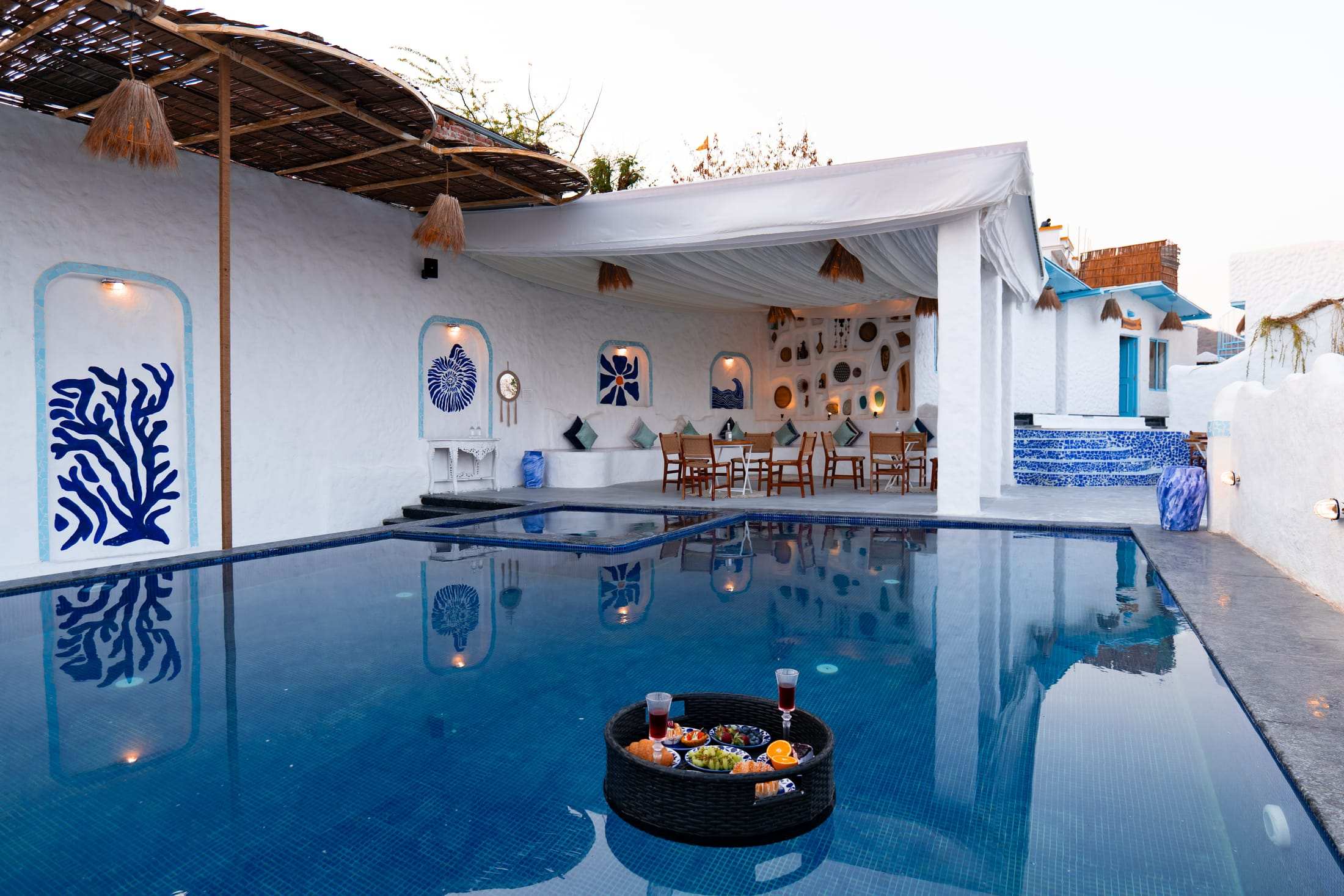 Floating tray in the pool in front of the white pavilion and blue ceramic decor