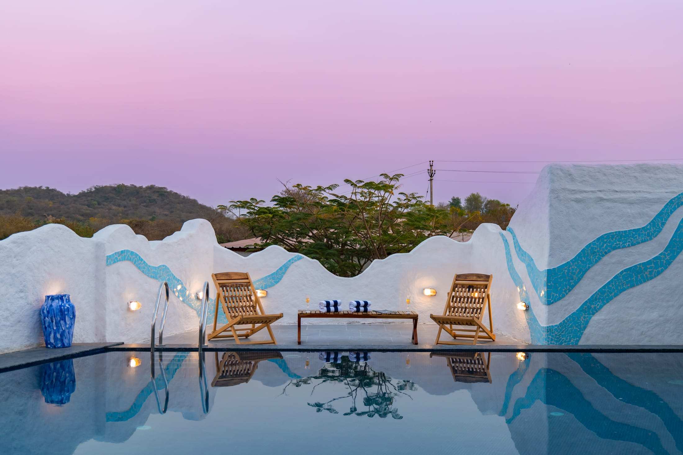 Loungers by the pool under a pink and lilac sunset sky