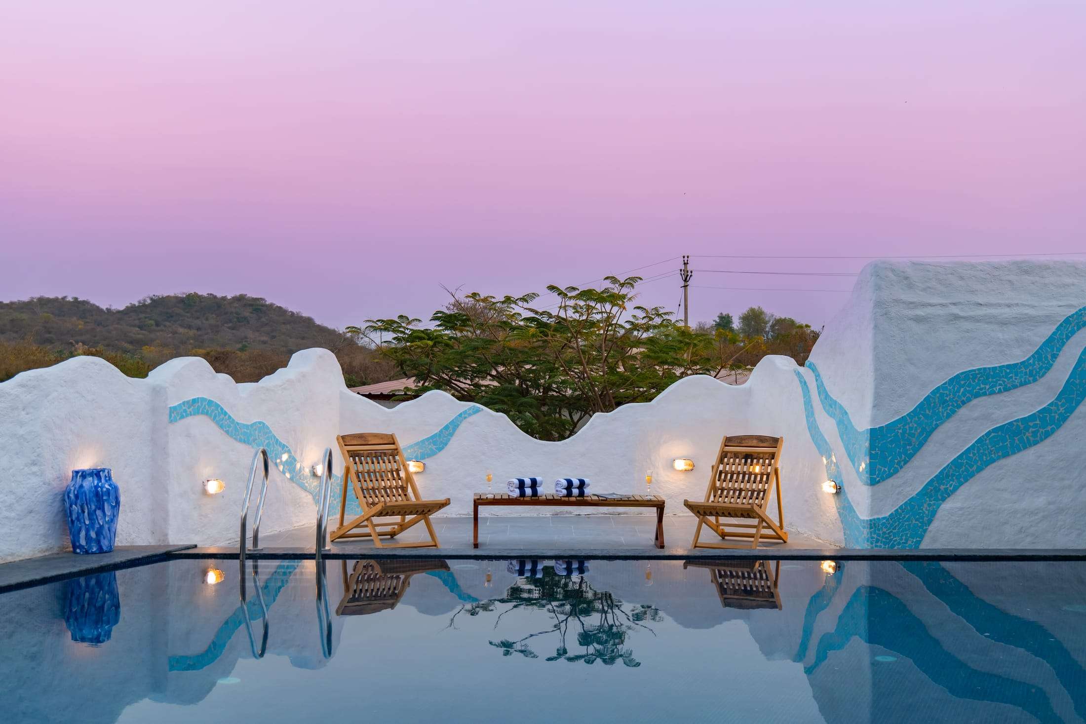 Loungers by the pool under a pink and lilac sunset sky