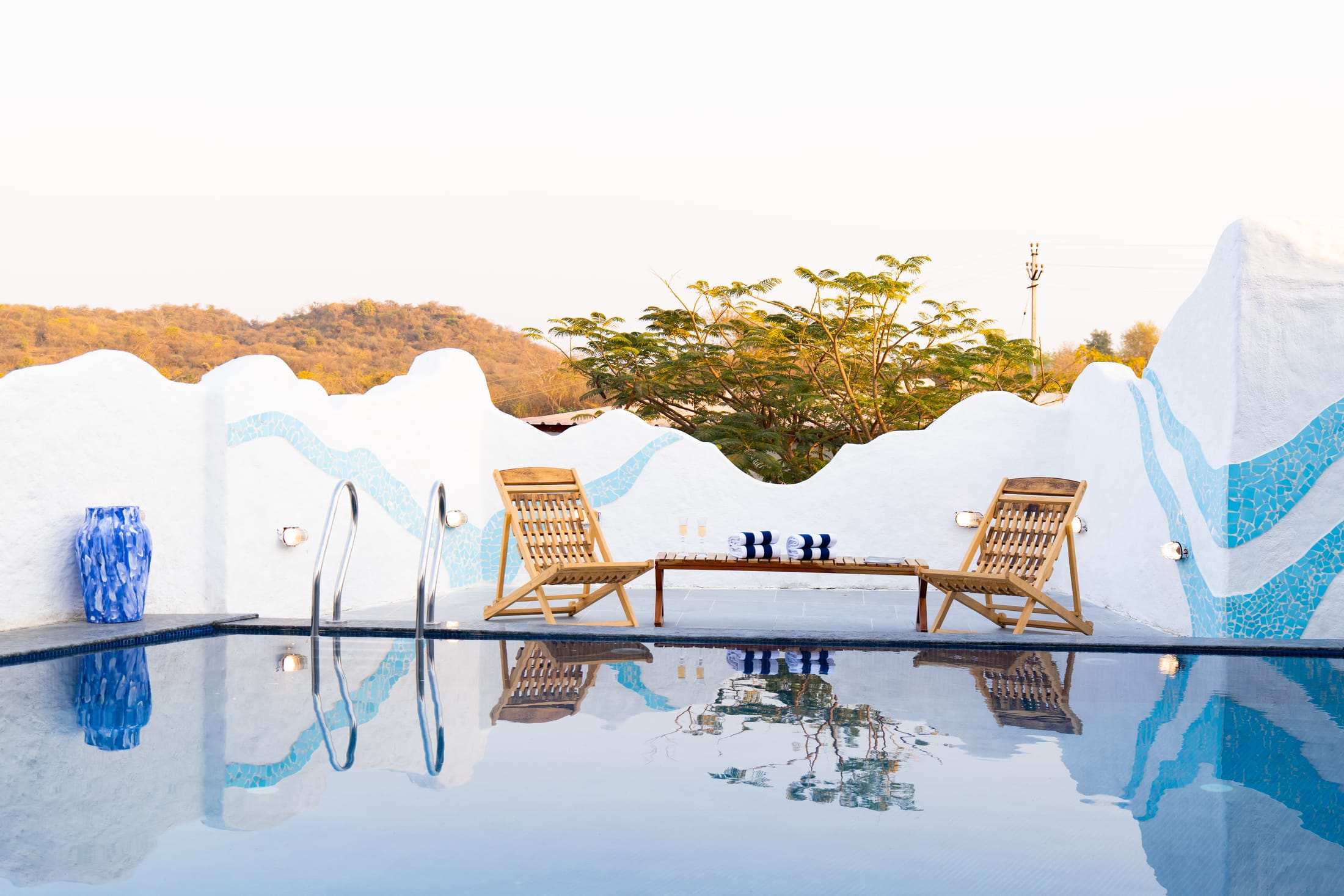 Two wooden loungers by the pool facing the hills