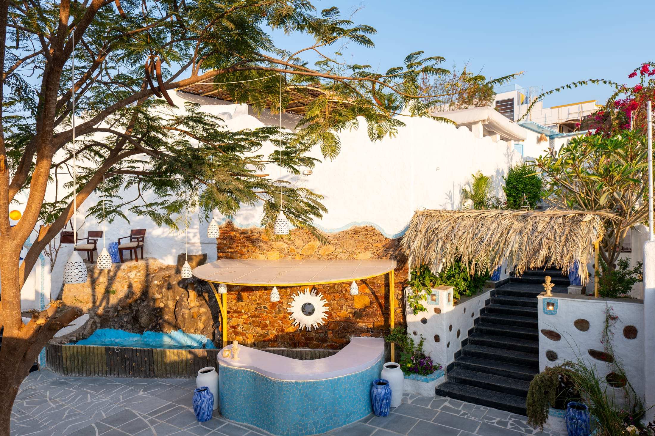 Reception courtyard with a rock water feature, thatched shade and stairs