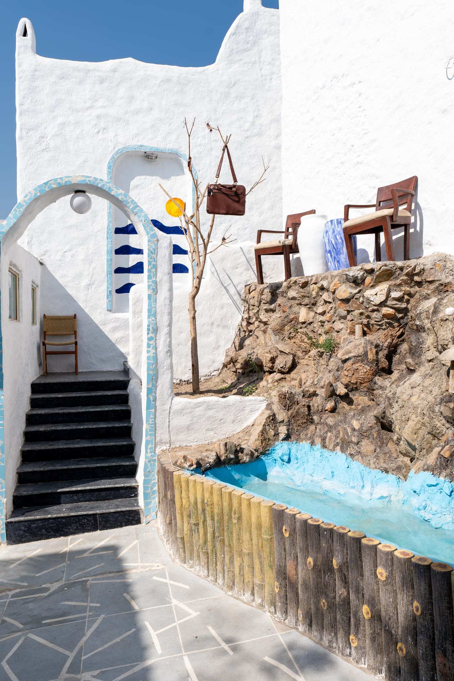 Rock waterfall beside white steps and a blue arch at the entrance