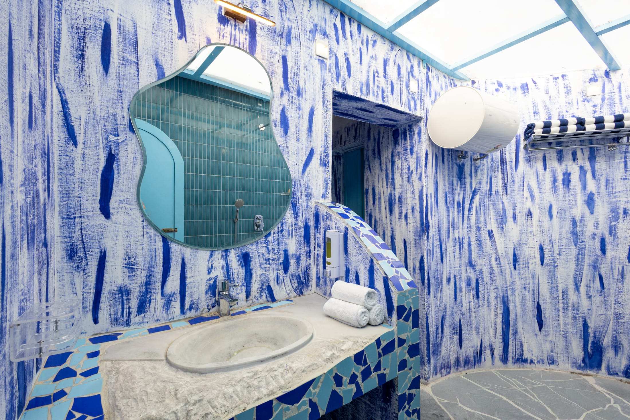 Designer blue-tiled bathroom in the Santorini Suite with a round mirror