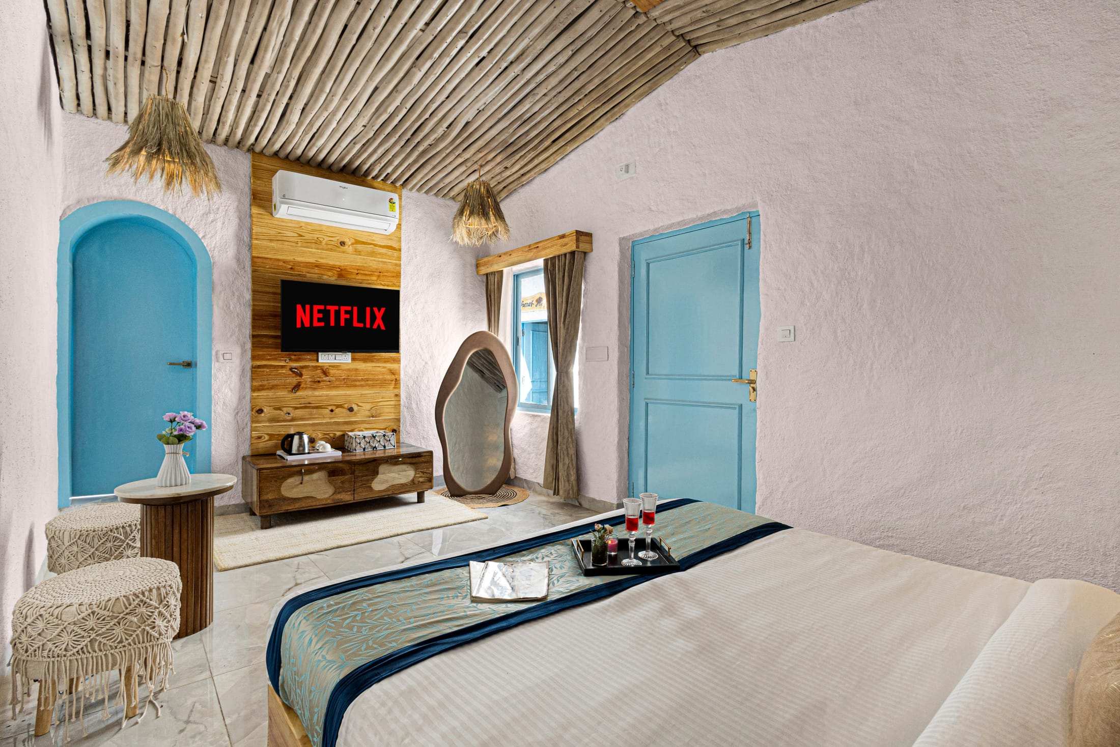 Santorini Suite TV wall with an organic-shaped mirror and a blue arched door