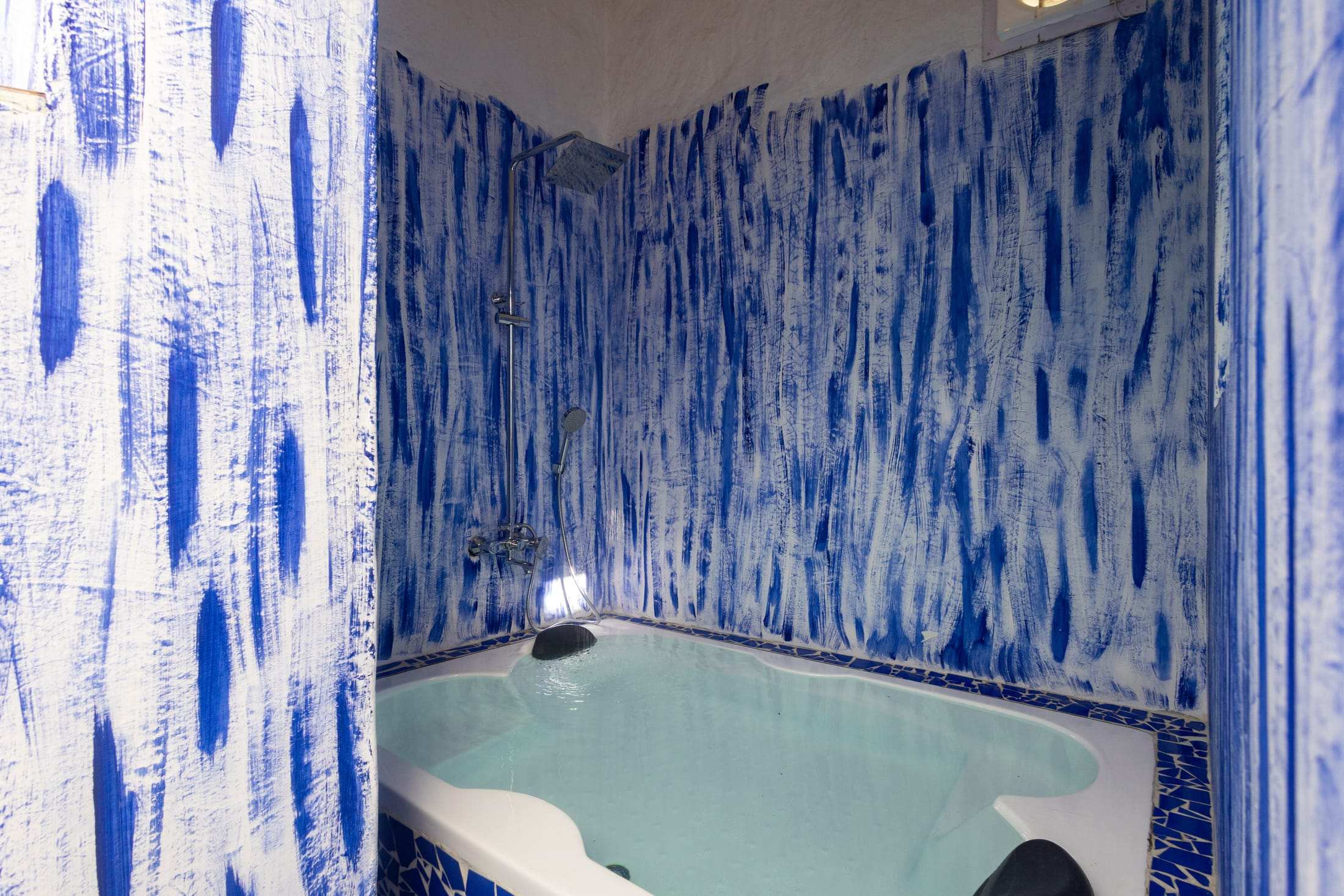 Two-seater bathtub surrounded by hand-painted blue tie-dye walls in the Santorini Suite
