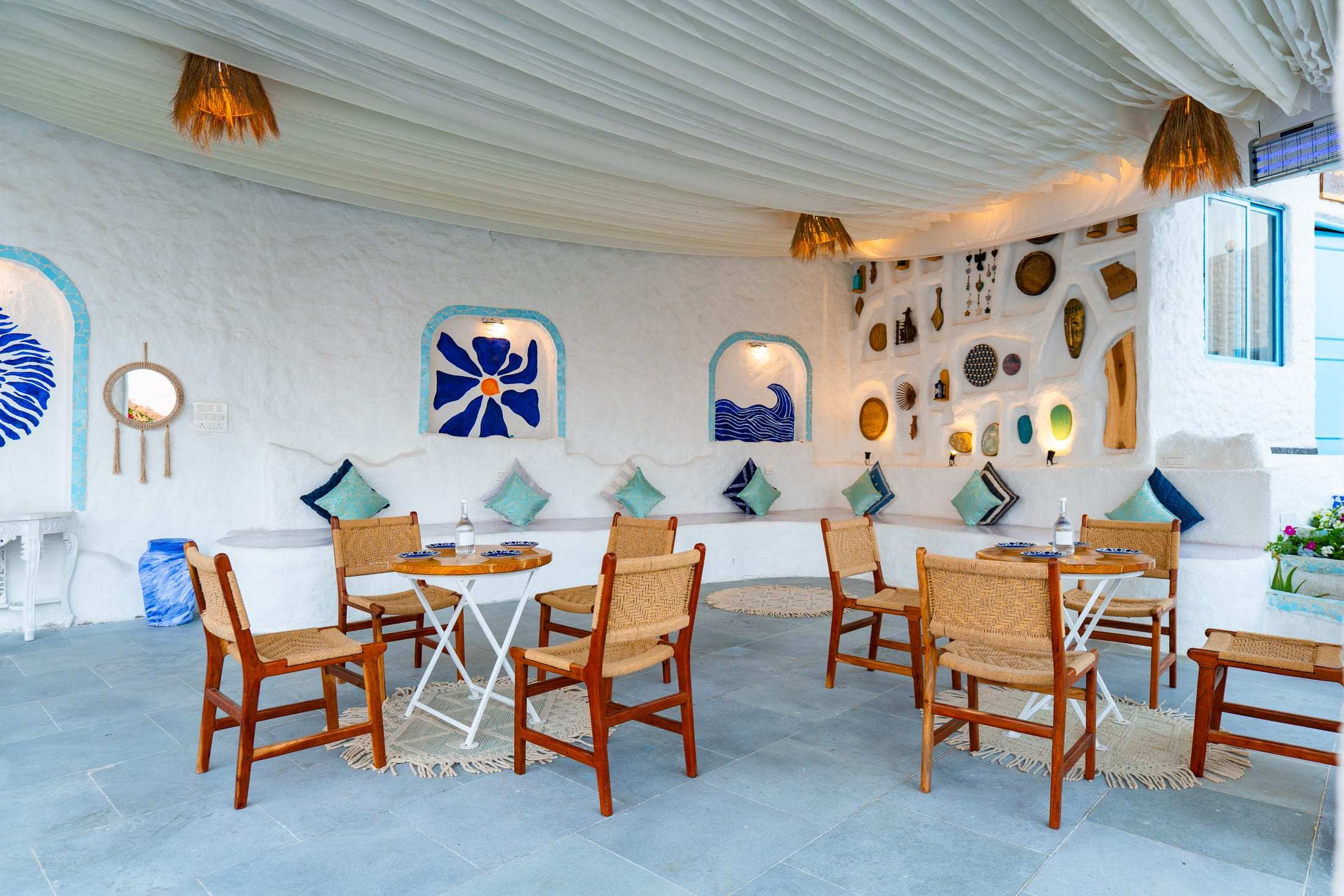 Lounge sit-out with handcrafted wall art, cane chairs and blue cushions