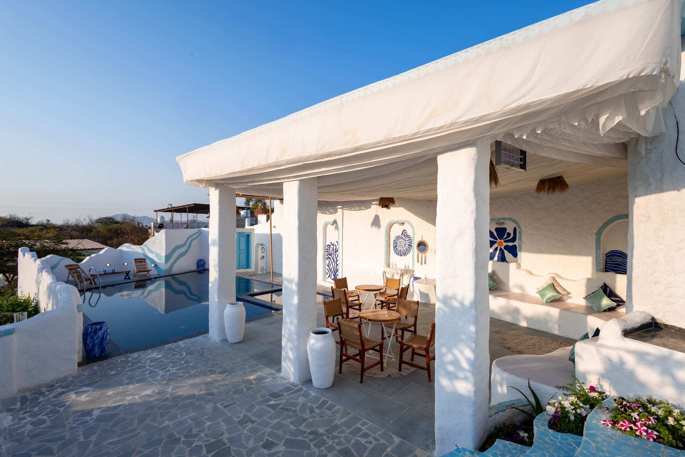 Covered sit-out with white pillars and a view over the pool