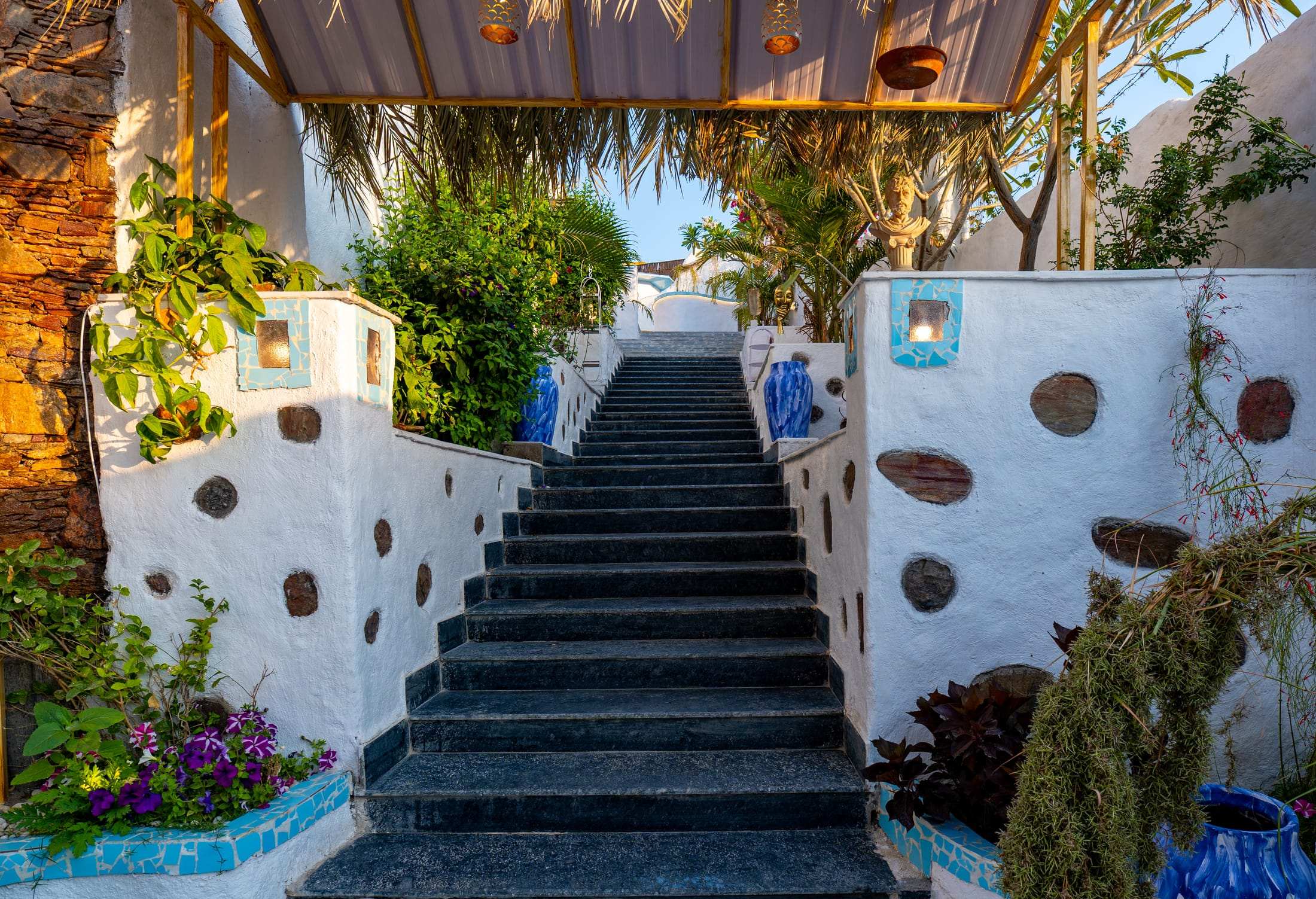 Stone stairway flanked by white walls, palms and blue pots