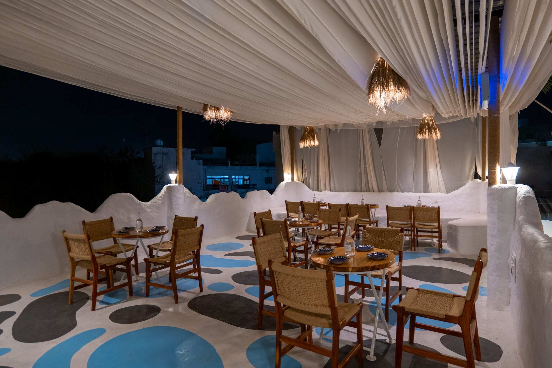 Terrace café under a draped canopy with pendant lights and blue-dot flooring