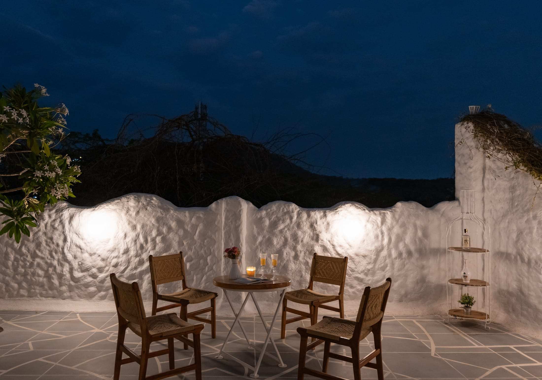 Night seating on the terrace against a textured white wall with round lights