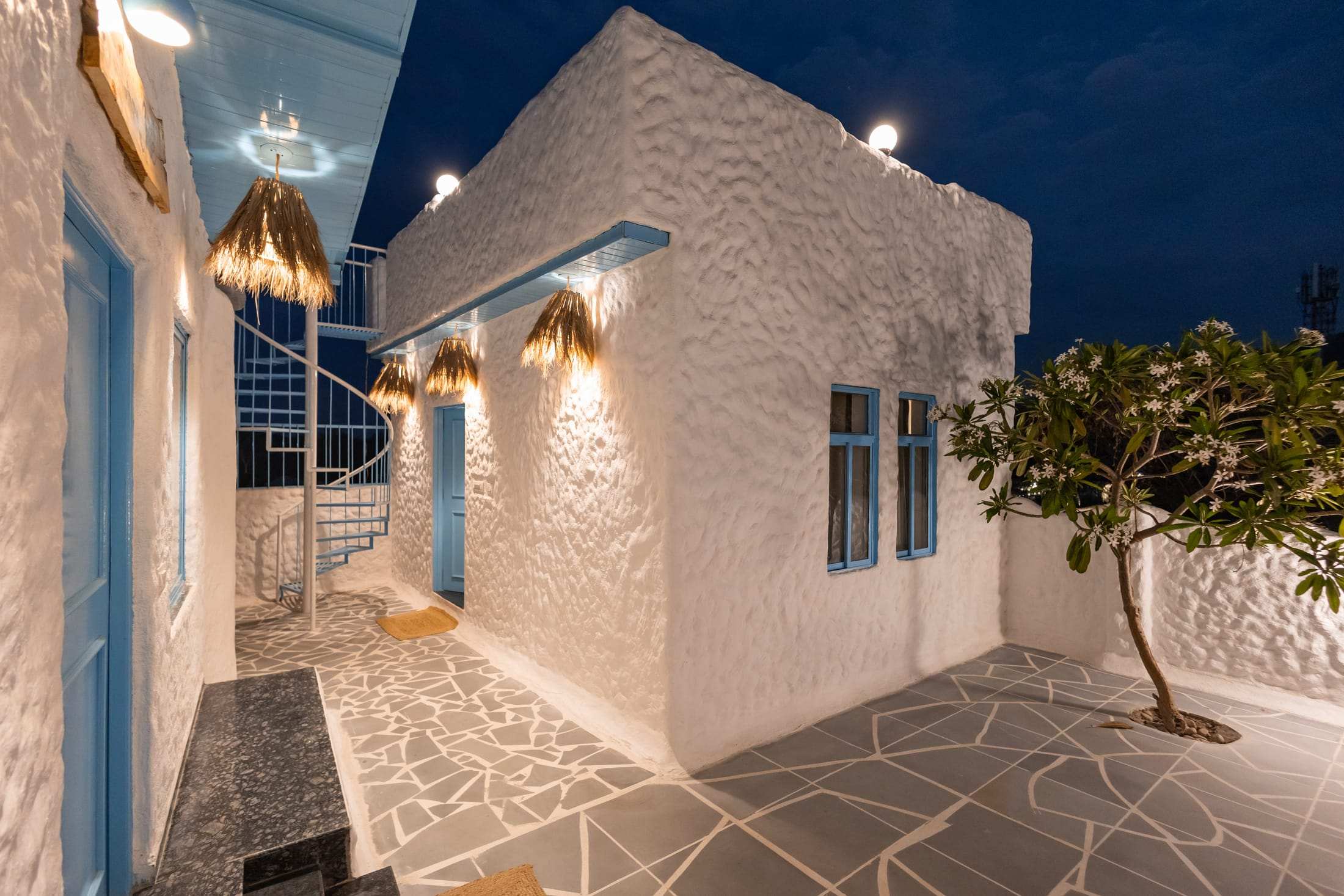 Night view of the villa courtyard with a tree and softly lit white walls