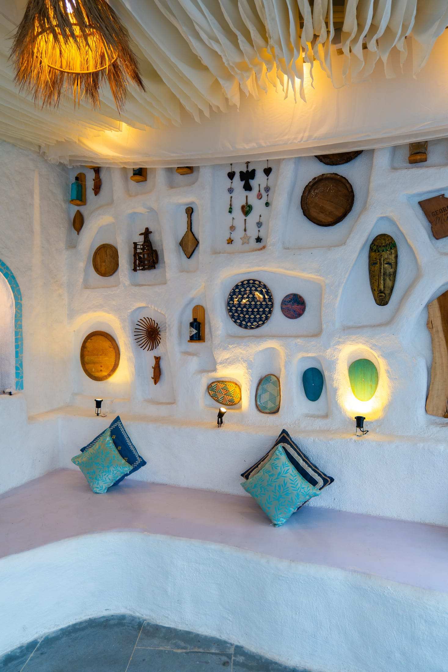 White wall niches filled with handcrafted plates, shells and lamps