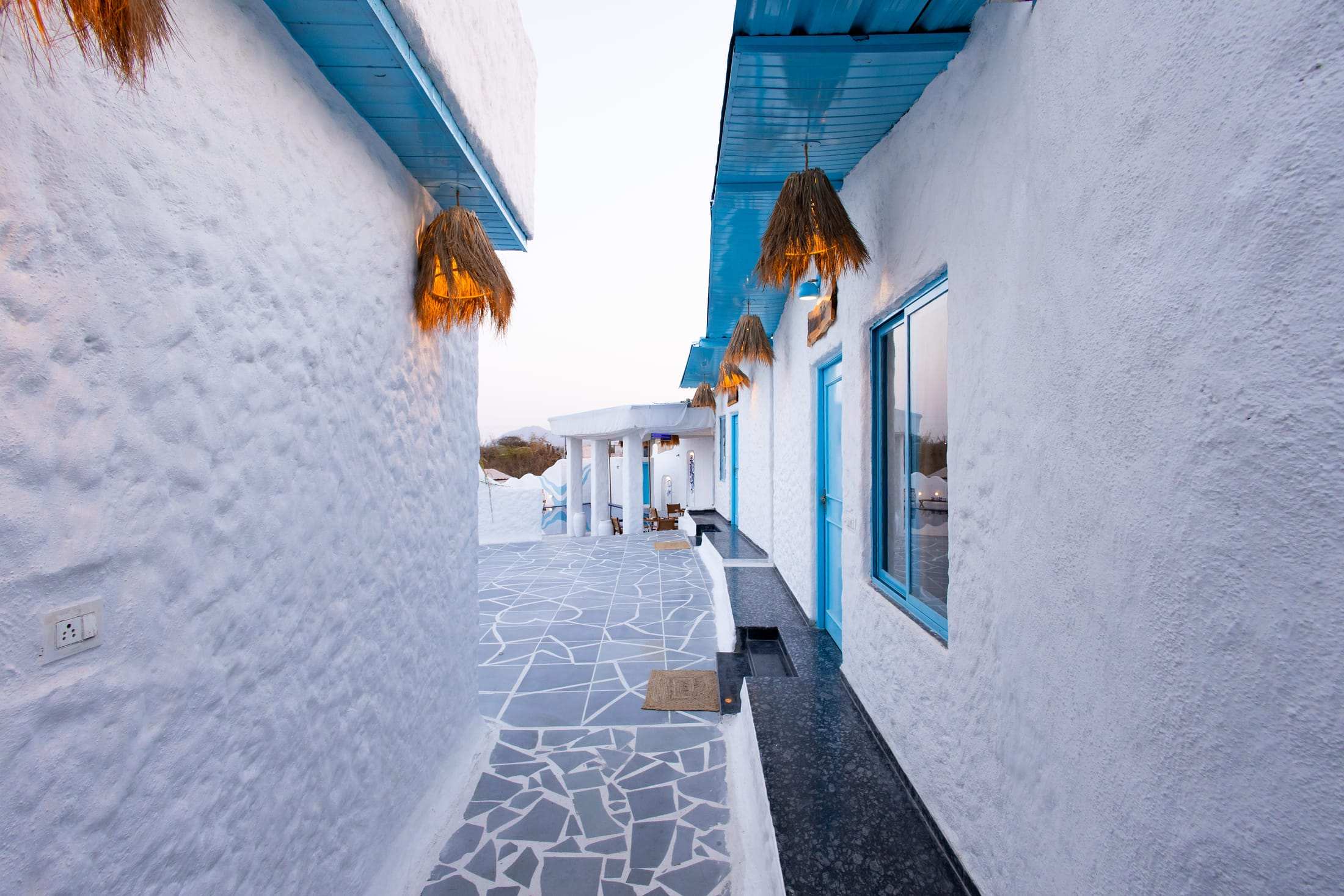 A narrow whitewashed lane with blue doors and stone paving inside the villa